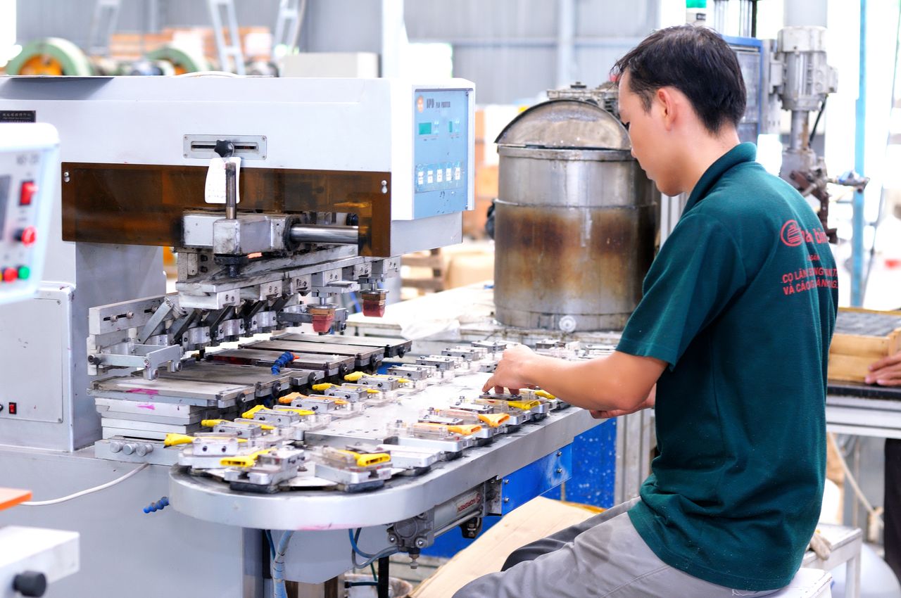 about-04 Asian male worker focused on operating machinery in a modern factory setting.