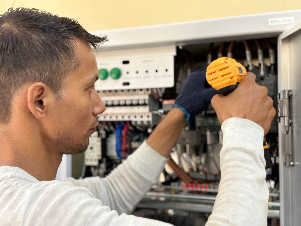 about-01 Focused technician using a drill on an electrical panel, showcasing expert workmanship.