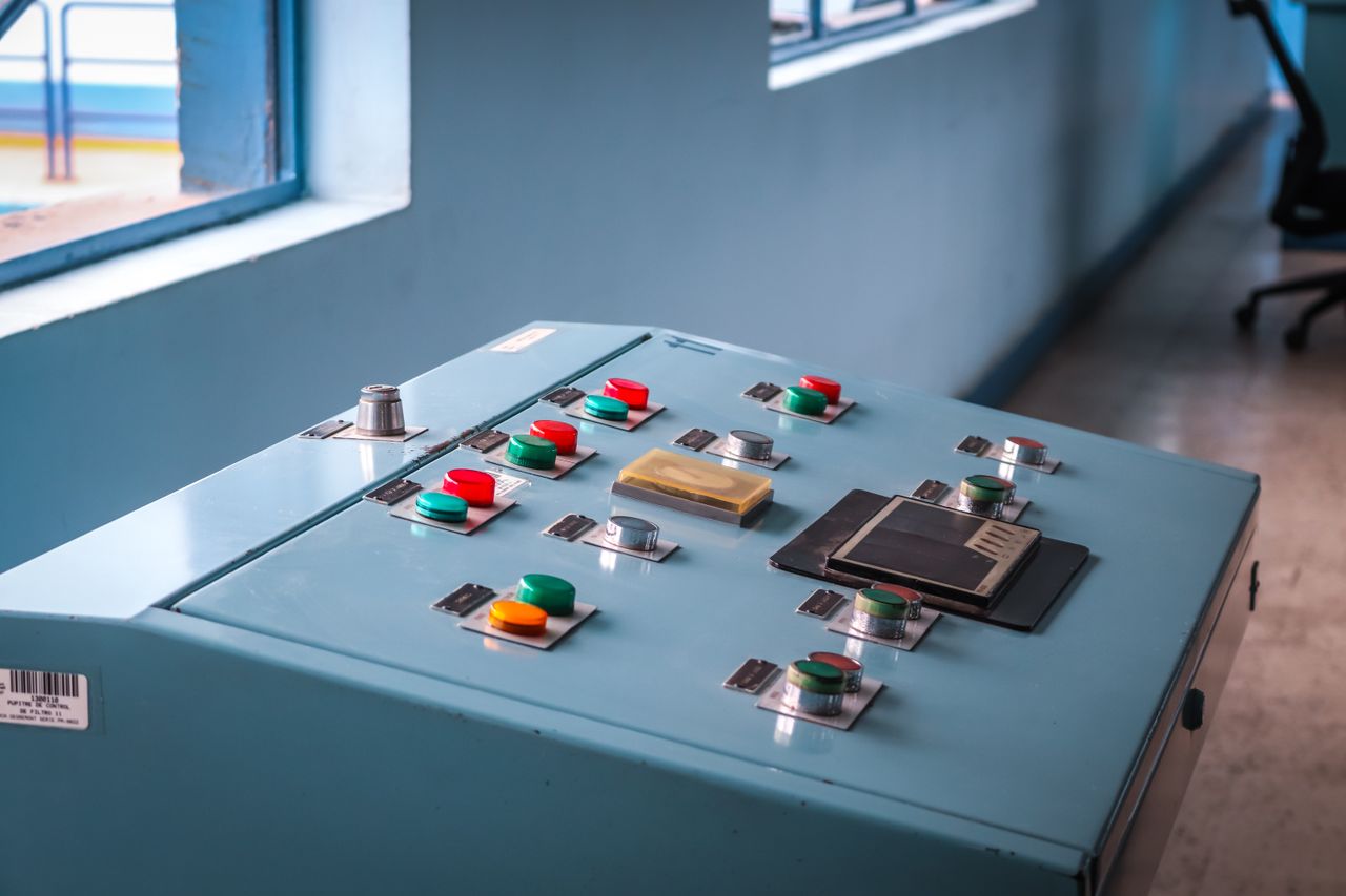 services-01 Close-up of an industrial control panel with colorful buttons in a factory setting.